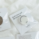 White phone pop socket with the uplifting message "God is love and He loves me," packaged on a matching card, inspiring faith and encouragement in everyday life.