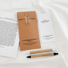 God is Love Pen Set with Bookmark displayed on a soft fabric background, featuring uplifting messages and elegant kraft packaging.