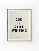 God Is Still Writing Christian poster inspired by Philippians 1:6 in a natural wood frame
