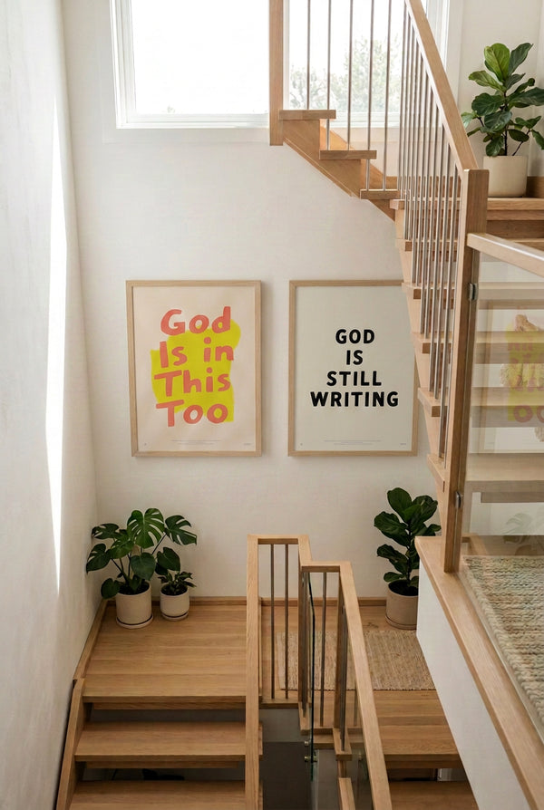 God Is Still Writing Christian poster displayed beside a staircase in a bright modern home