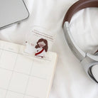 God Loves Us acrylic Christian bookmark featuring a Jesus and sheep illustration, styled with a planner, laptop and headphones