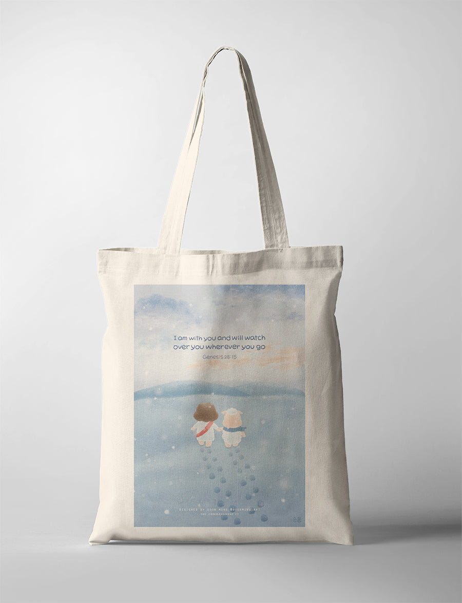 A heartwarming illustration of Jesus and a fluffy sheep walking together on a snowy path, symbolizing companionship and divine protection. The tote bag features the comforting Bible verse, 'I am with you and will watch over you wherever you go,' from Genesis 28:15.