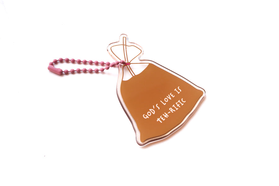 Angled view of drink bag acrylic keychain featuring “God’s Love Is Teh-rific” with pink ball chain