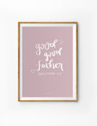 A framed wall art piece featuring the phrase "Good Good Father" from Galatians 4:7, written in soft, handwritten typography against a muted lavender background, with small decorative stars.