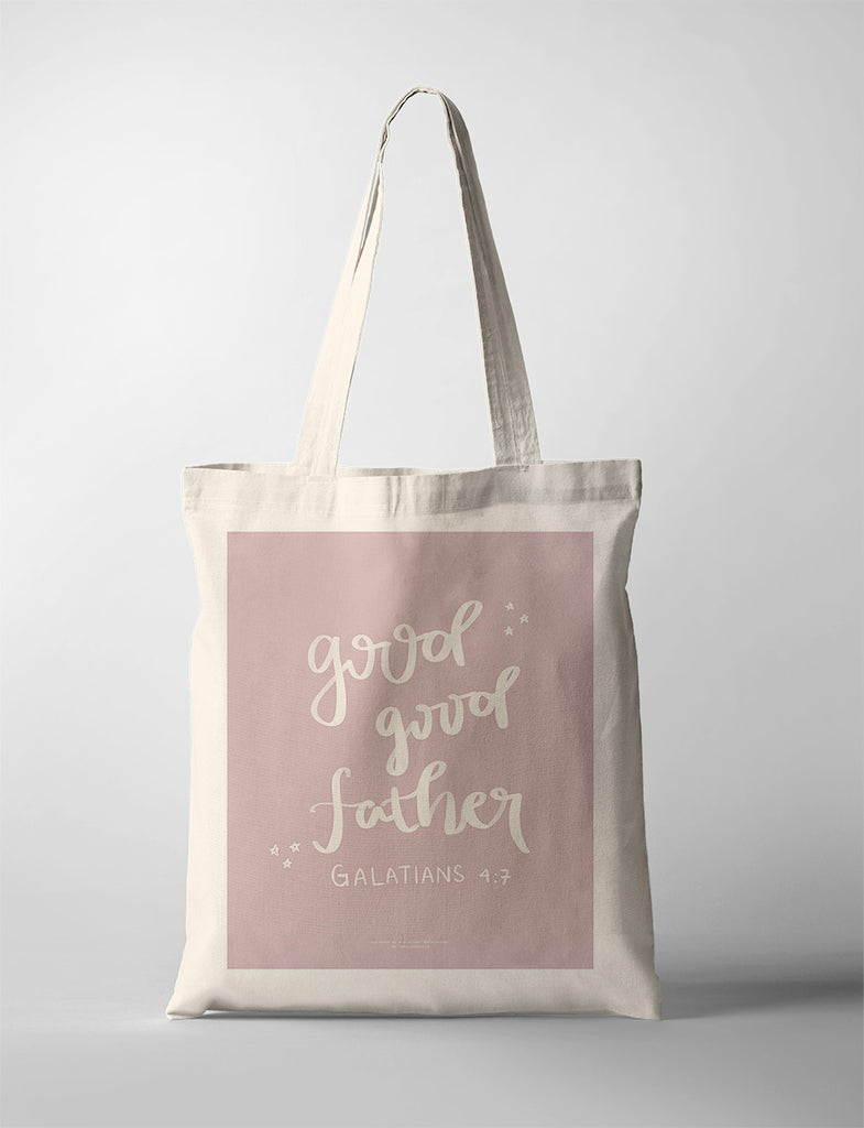 A beige tote bag featuring the heartfelt message "Good Good Father" from Galatians 4:7, designed in soft handwritten text on a muted pink background with small star accents for a serene and inspirational touch.