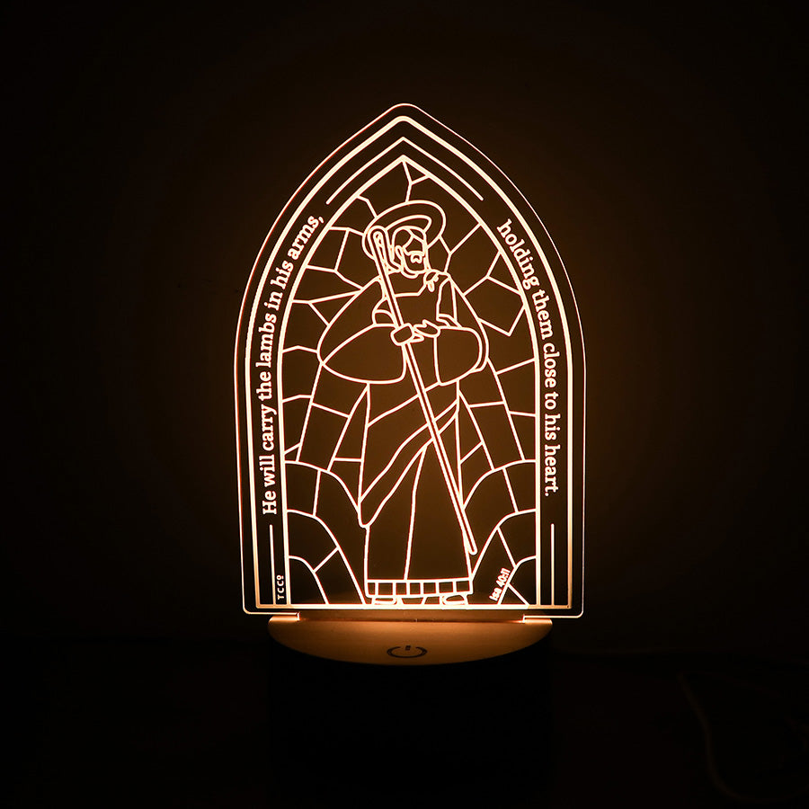 Christian LED lamp with an arch window design featuring Jesus as the Good Shepherd, holding a staff, and the text 'He will carry the lambs in his arms, holding them close to his heart' from Isaiah 40:11.