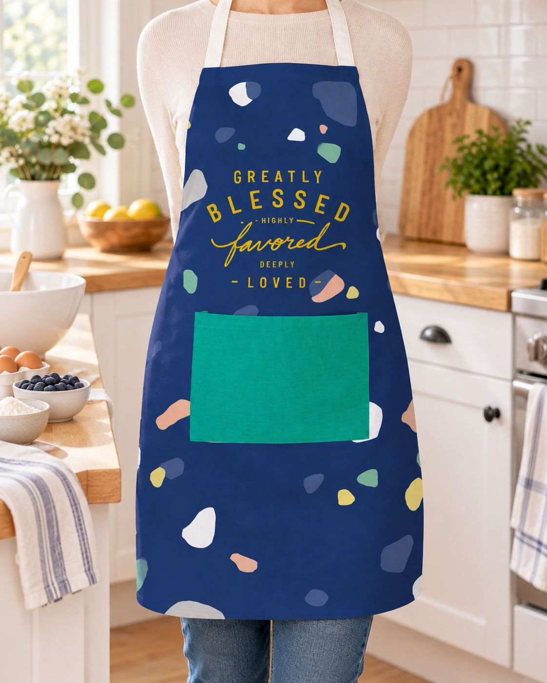 Greatly Blessed Highly Favored Deeply Loved navy apron worn in a bright kitchen