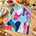 Greatly Blessed colourful Christian tea towel spread on a breakfast table with coffee, pastries and fruit
