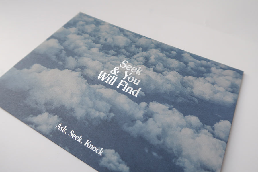 A detailed view of a postcard showing a serene sky filled with clouds and the uplifting message "Seek & You Will Find" with the additional text "Ask, Seek, Knock," encouraging hope and perseverance.