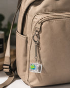 Hallelujah light-up keycap keychain clipped to a beige backpack