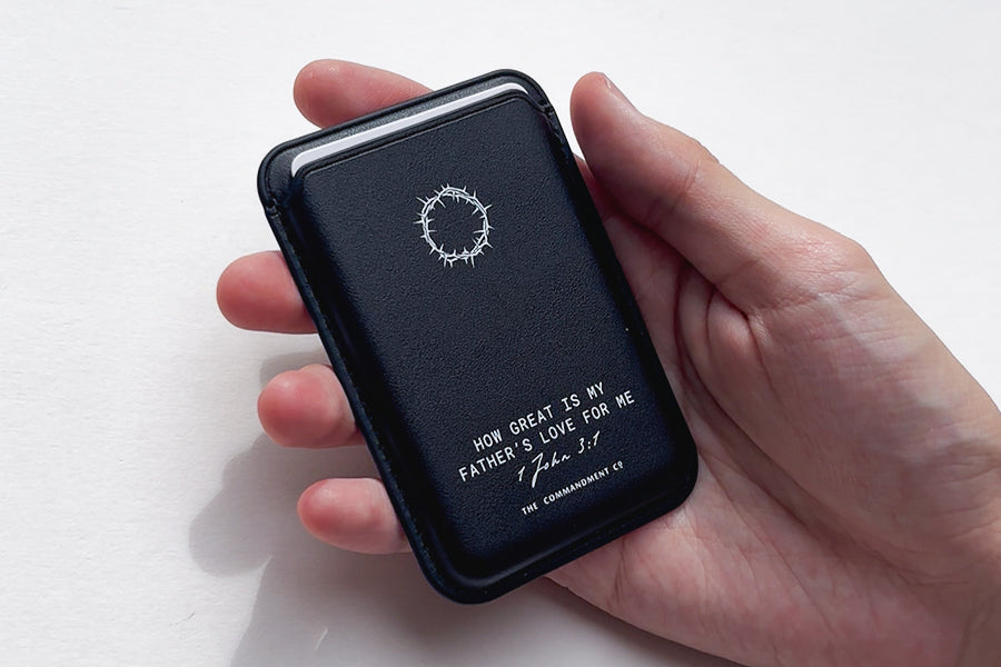 A hand holding a Black Leather Magsafe Wallet