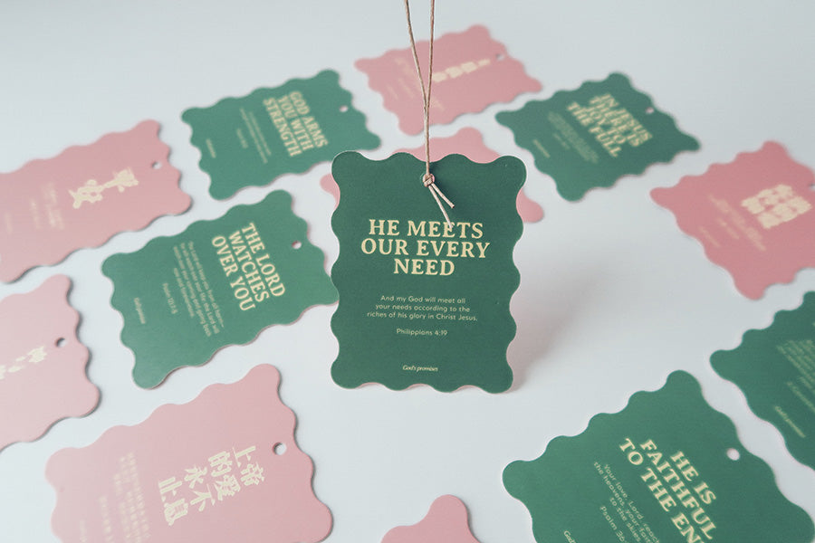 Christian Christmas tree hanging ornament or bookmark with the Bible verse 'He Meets Our Every Need' from Philippians 4:19, featuring a green scalloped design with a twine string.