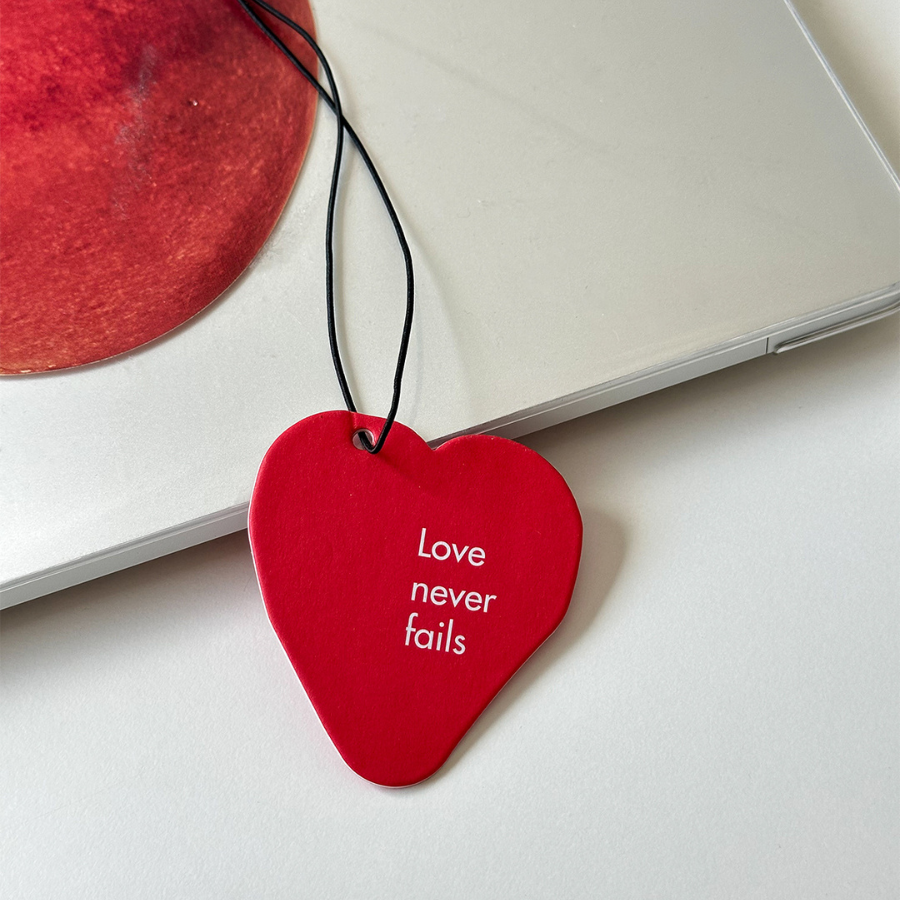 Red heart scent tag with the uplifting message "Love never fails," perfect for inspiring simple happiness and sharing encouragement in everyday life.