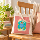 Hello Child Chocolate Biscuit tote bag styled on a sunlit wooden bench, with the canvas straps resting across the bag.