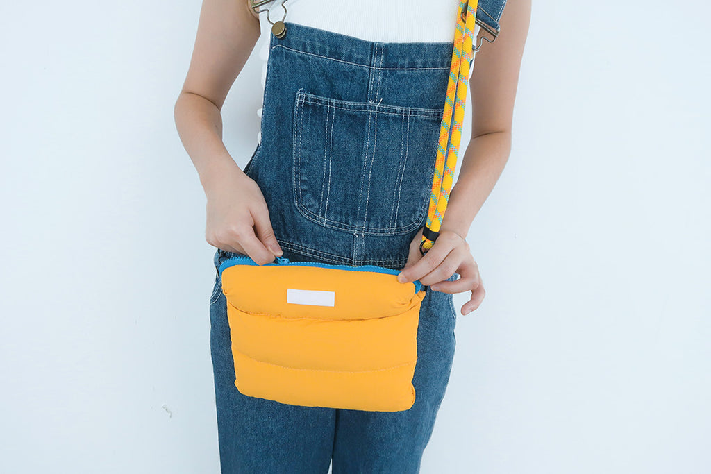 Person holding the Yellow Pong Pong Bag, emphasizing its soft, fluffy texture and multipurpose storage capabilities.