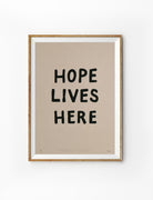 Hope Lives Here Christian poster in a light wood frame