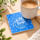 I Can Do All Things Through Him Who Strengthens Me blue coaster styled with a coffee mug on a sunlit wooden table