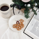 I Love You" dessert plate featuring a cute illustration of Jesus, topped with pretzels, beside a coffee mug, Bible, and Christmas tree, sharing a message of love and simple happiness from Jincha God.