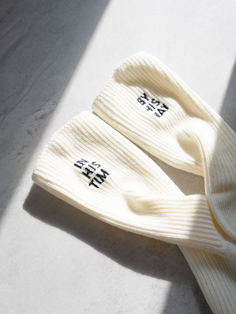 Cream ribbed knit socks with black embroidery that reads "IN HIS TIME," photographed on a light surface; faith-inspired, wearable reminder from The Commandment Co.
