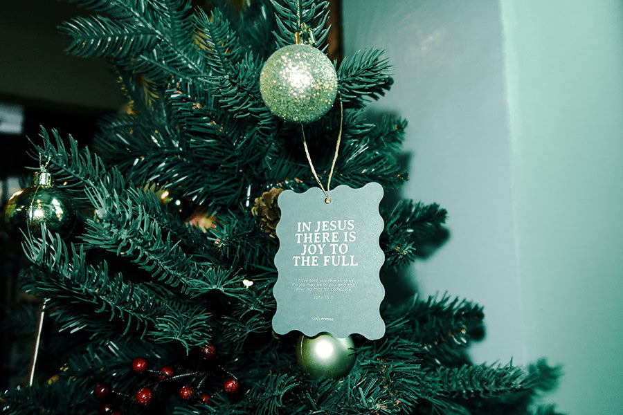 Christian Christmas tree hanging ornament with the Bible verse 'In Jesus There Is Joy to the Full' from John 15:11, displayed on a decorated Christmas tree with green branches and ornaments.