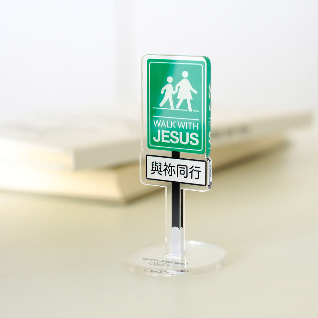 Green 'Walk with Jesus' acrylic sign in Chinese and English displayed on a desk with books in the background, emphasizing faith and devotion.