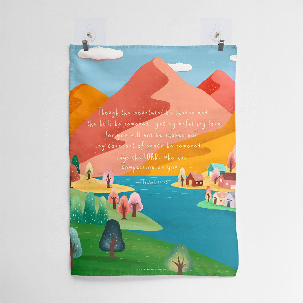 Christian wall art with Isaiah 54:10, 'Though the mountains be shaken and the hills be removed, yet my unfailing love for you will not be shaken,' displayed over a vibrant mountain landscape with colorful trees and a serene river.