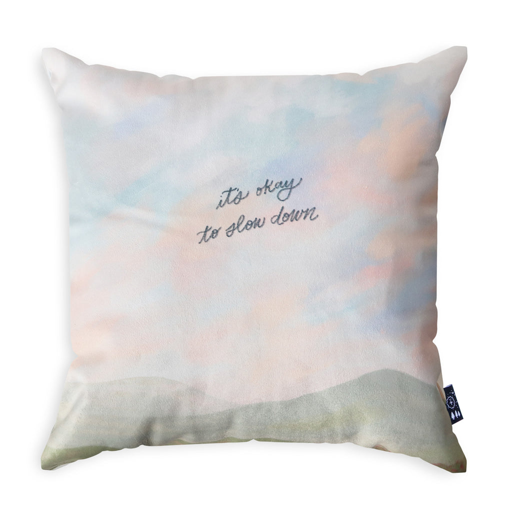 Decorative throw pillow with the text 'It's okay to slow down,' featuring a soft pastel design and a peaceful aesthetic for Christian faith-based home decor.