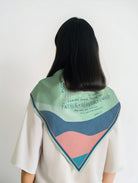 Back view of a model wearing a colorful abstract scarf featuring James 1:17 “Every good gift is from above” in a modern Christian design by The Commandment Co.