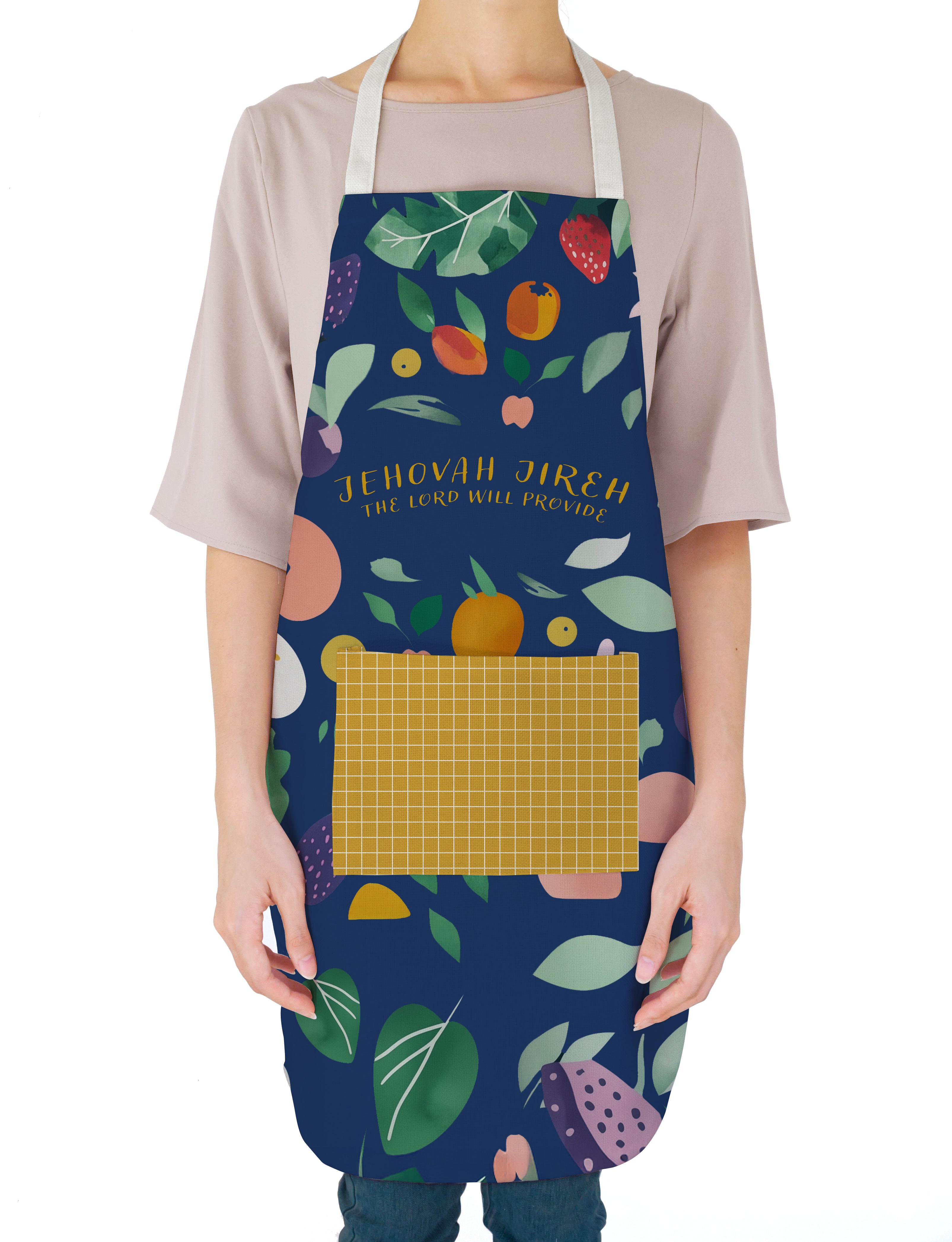  A person wearing a colorful "Jehovah Jireh The Lord Will Provide" apron with vibrant fruit and leaf illustrations, reflecting faith, simple happiness, and encouragement in daily living.