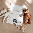 Christian cotton linen wall decor with text "God loves us not because of what we do but because we are his children", styled with sheep and bear plush toys in a warm neutral room