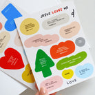 Colorful sticker sheet titled 'Jesus Loves Me' with various Bible verse quotes and Christian inspirational messages in playful shapes.