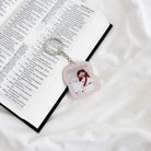 Christian acrylic keychain featuring Jesus and a sheep beside an open Bible, with a reminder of God’s unconditional love