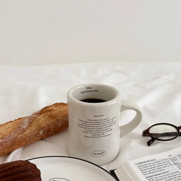 Jin Cha God off-white vintage ceramic mug with Dear Father prayer design styled with coffee, bread and Bible