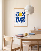 Joy Found Me poster displayed in a bright dining room with light wood furniture and pastel tableware