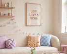 Joy Lives Here Christian wall art styled in a colourful living room