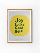 Joy Looks Good Here Christian poster with dark green lettering on a hand-painted yellow circle