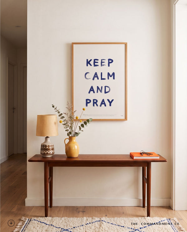 Keep Calm and Pray Christian poster displayed above a wooden console table in a warm neutral entryway