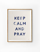 Keep Calm and Pray Christian poster with navy lettering displayed in a wooden frame against a white background