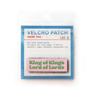 Pink Velcro tag with green text 'King of Kings, Lord of Lords,' an inspirational Christian embroidered patch for clothing and accessories.