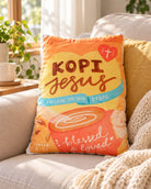 Kopi Jesus Coffee plush toy styled on a sofa in a warm, sunlit living room.
