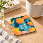 Let the Peace of Christ Rule in Your Heart Christian coaster with colourful fruit artwork beside a coffee cup in a warm home setting.