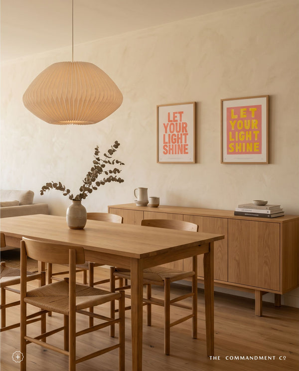 Coral Let Your Light Shine Christian poster displayed with a pink and yellow poster in a warm dining room