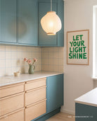 Let Your Light Shine green Christian poster displayed in a modern kitchen with teal cabinets