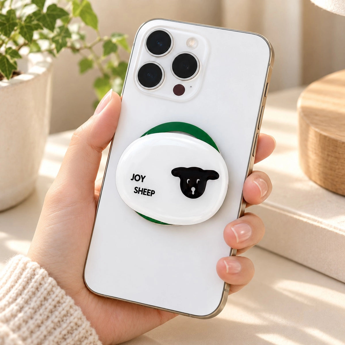 Let’s Be Joyful Sheep spinner phone grip attached to a white smartphone held in hand.