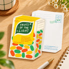 Light Fruity Mints LOVE SUPERMARKET shaped card photographed on a warm wooden desk with its postcard back