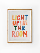 Light Up The Room Christian poster with colourful hand-drawn lettering displayed in a wooden frame on a white background