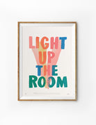 Colourful Light Up The Room Christian poster with hand-drawn lettering and abstract brushstrokes displayed in a wooden frame