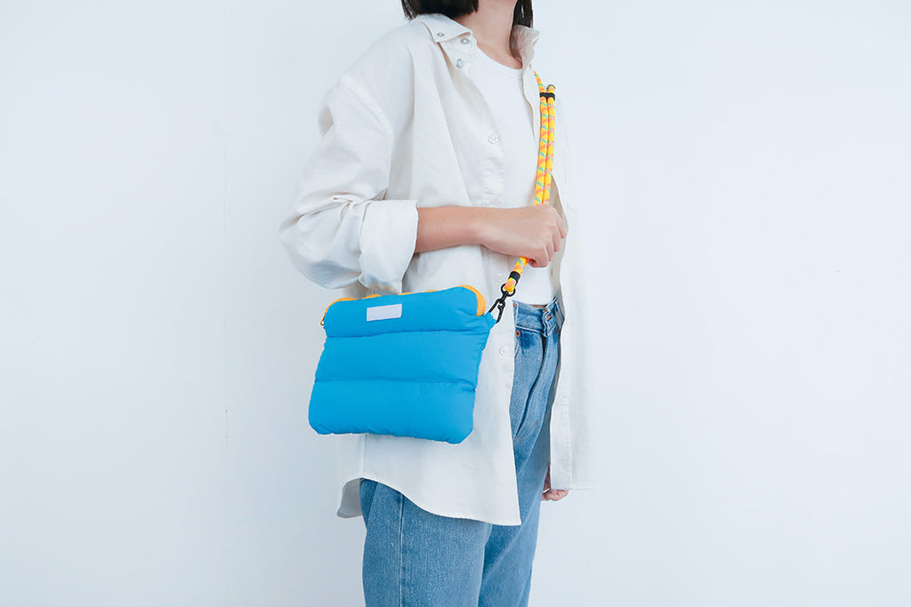 Lightweight cyan padded bag with colorful strap, suited for crossbody carry and outdoor activities