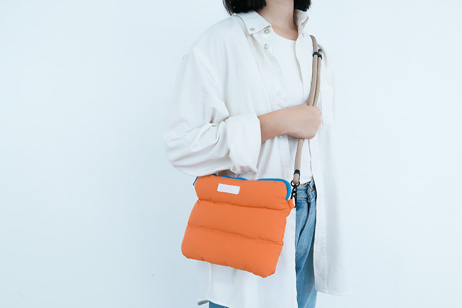 Woman carrying the Orange Pong Pong Bag over the shoulder, ideal for both storage and fashion.