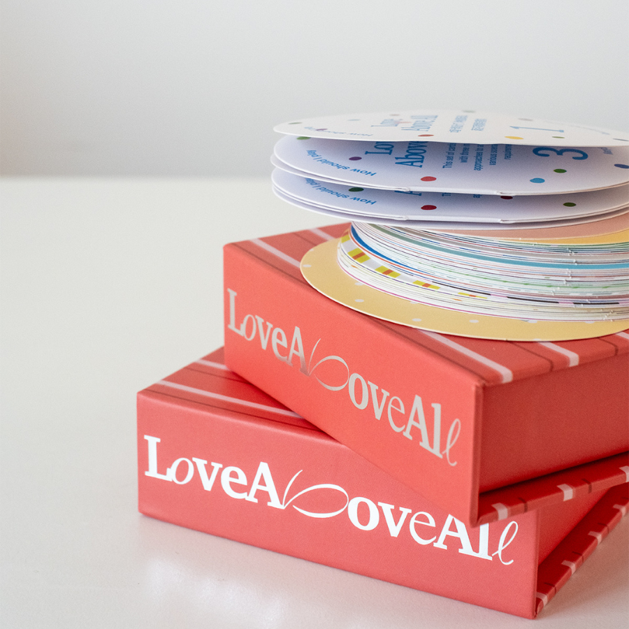 Hands fanning out Love Above All cards, an interactive faith-based card game designed to spark conversations and deepen relationships.